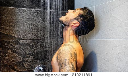 Close up of Attractive Young Bare Muscular Young Man with Tattoos Taking Shower