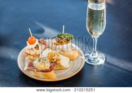 Beautiful and colorful set of pinchos, traditional spanish snack related to tapas, with glass of wine outdoors on the table