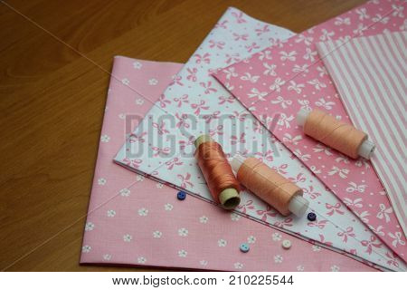 Multicolored cuts of fabric with coils of thread on the background of boards