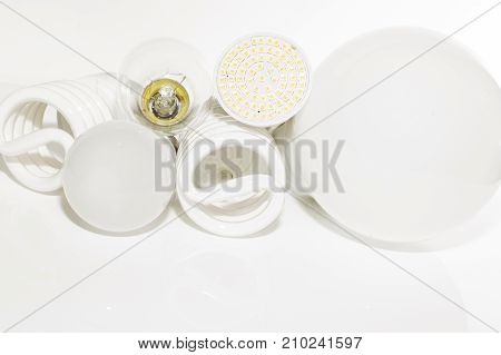 Several different led bulbs and compact fluorescent lamps with the size of the male screw base E27 on a light background