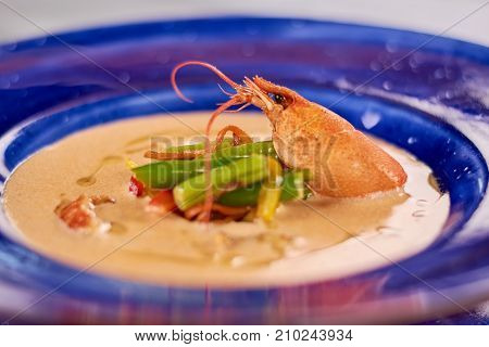 Cream soup with crayfish tails and vegetables. Tasty soup puree with vegetables and crayfish. Delicious dinner on plate close up.
