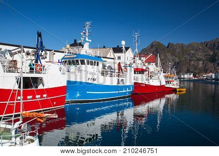 Henningsvaer Norway - August 19 2017: Picturesque fishing port in Henningsvaer on Lofoten islands Norway with typical red wooden buildings and small fishing boats