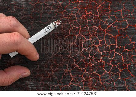 Young man holding a cigarette in hand. Concept of tobacco addiction and the danger of smoking. Consequences of nicotine dependence. Harmful habit. Destruction of the human body. Close up view.
