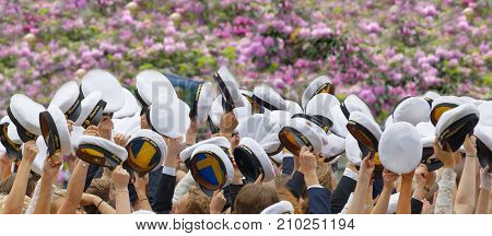 STOCKHOLM SWEDEN - JUN 13 2017: Hands holding many swedish white graduation caps lilac flowers in the background at the dance school Balettakademien June 13 2017StockholmSweden