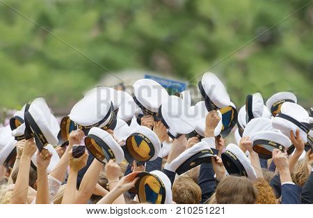 STOCKHOLM SWEDEN - JUN 13 2017: Hands holding many swedish white graduation caps green trees in the background at the dance school Balettakademien June 13 2017StockholmSweden