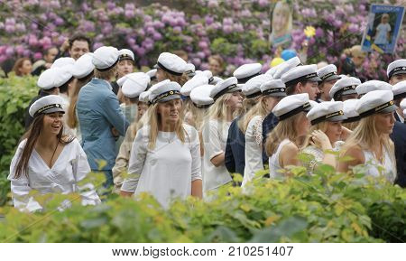 STOCKHOLM SWEDEN - JUN 13 2017: Happy swedish teenagers wearing graduation caps lilac flowers in the background at the dance school Balettakademien June 13 2017StockholmSweden