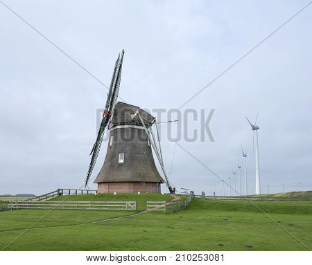 old windmill goliath at roodeschool in the dutch province of groningen between row of modern wind turbines