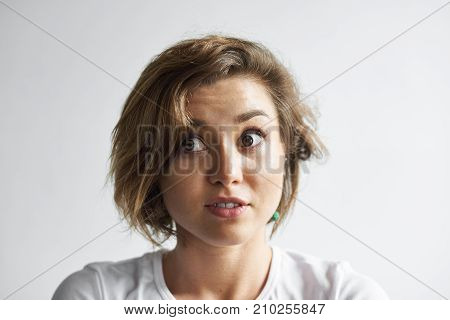 Cute student girl looking sideways being at loss popping her eyes out feeling confused and puzzled as she doesn't know right answer on professor's question during History class at university