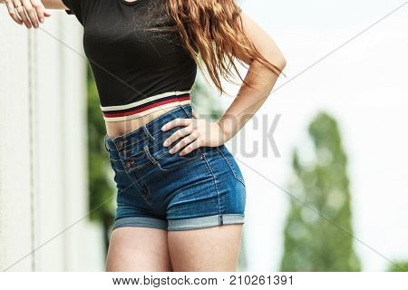 Woman showing her sexy curves. Hips and legs body part in short denim shorts.