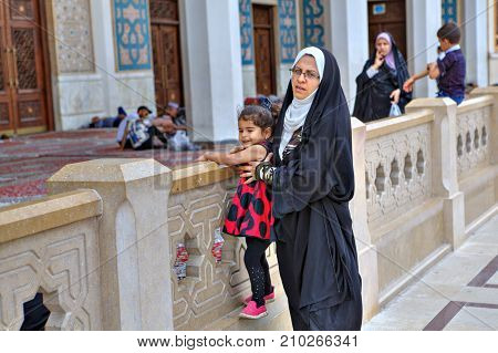 Fars Province Shiraz Iran - 19 april 2017: Shah Cheragh Shrine Muslim woman wearing an Islamic veil strolls in the inner courtyard of the mosque with a little girl.