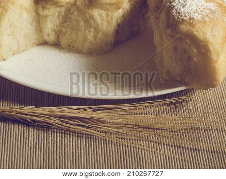 Homemade pastries on a white dish and wheat spikes in vintage processing