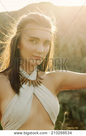 Primitive Woman Sitting On A Rock At The Sunset. Amazon Woman