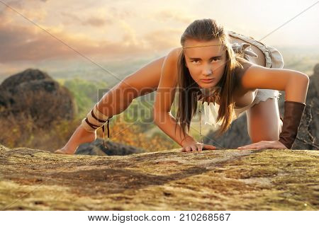 Primitive Woman On A Rock At The Sunset. Amazon Woman
