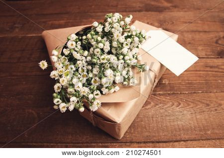 Bouquet of camomile field wrapped in kraft paper on a wooden table