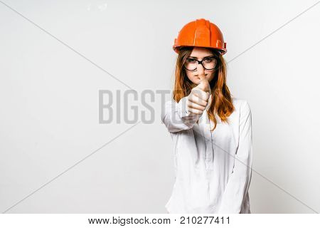 young red-haired girl in protective orange helmet showing thumb up