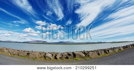 Travel to Iceland. road and river in a bright sunny mountain landscape. Vatna volcano covered with snow and ice on tne background.