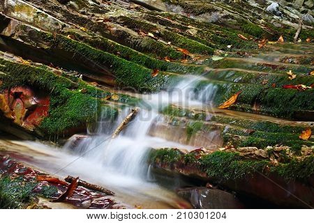 Rocks covered with moss with a flowing streams of the mountain creek