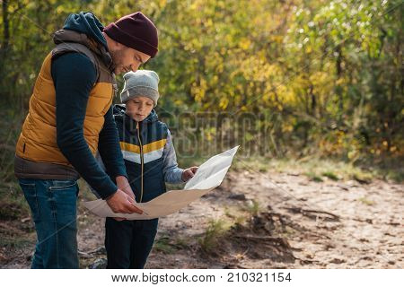 Father And Son With Map In Forest