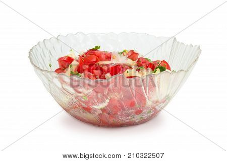 Vegetable salad of the sliced tomatoes white bell peppers onion and potherb in a glass salad bowl on a white background