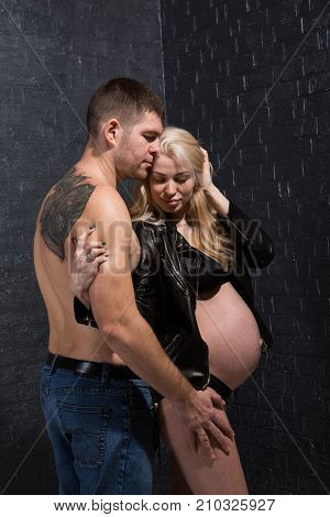 Beautiful pregnant couple in love on the background. Hands of husband on the tummy of his pregnant wife. Young man tenderly stroked pregnant belly of his wife. Husband kissing pregnant belly.