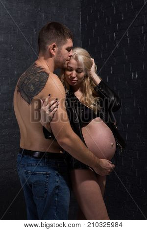 Beautiful pregnant couple in love on the background. Hands of husband on the tummy of his pregnant wife. Young man tenderly stroked pregnant belly of his wife. Husband kissing pregnant belly.