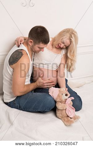 Beautiful pregnant couple in love on the background. Hands of husband on the tummy of his pregnant wife. Young man tenderly stroked pregnant belly of his wife. Husband kissing pregnant belly.