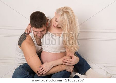 Beautiful pregnant couple in love on the background. Hands of husband on the tummy of his pregnant wife. Young man tenderly stroked pregnant belly of his wife. Husband kissing pregnant belly.