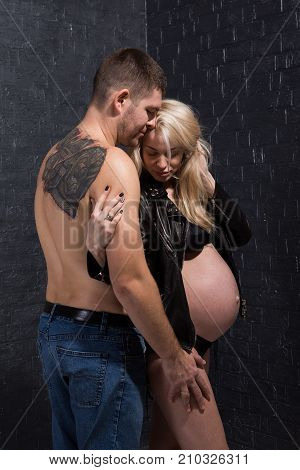 Beautiful pregnant couple in love on the background. Hands of husband on the tummy of his pregnant wife. Young man tenderly stroked pregnant belly of his wife. Husband kissing pregnant belly.