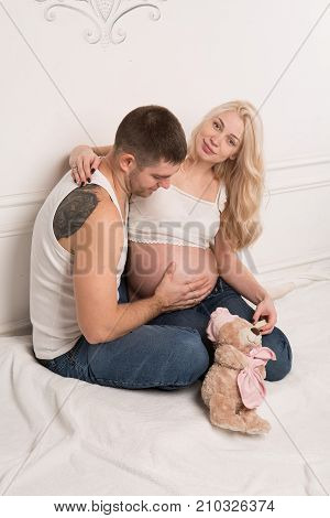 Beautiful pregnant couple in love on the background. Hands of husband on the tummy of his pregnant wife. Young man tenderly stroked pregnant belly of his wife. Husband kissing pregnant belly.