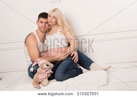 Beautiful pregnant couple in love on the background. Hands of husband on the tummy of his pregnant wife. Young man tenderly stroked pregnant belly of his wife. Husband kissing pregnant belly.