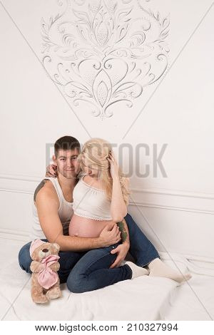 Beautiful pregnant couple in love on the background. Hands of husband on the tummy of his pregnant wife. Young man tenderly stroked pregnant belly of his wife. Husband kissing pregnant belly.