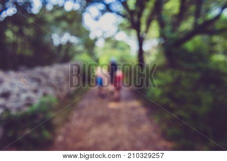 Family Hiking On Country Road With Rock Fence And Woods.