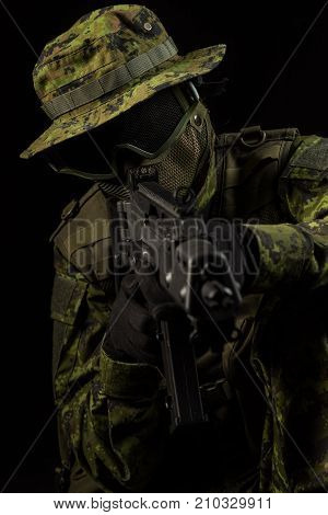 Portrait of armed woman with camouflage. Young female airsoft sniper observe with firearm. Soldier with gun in war black background. Military army people concept