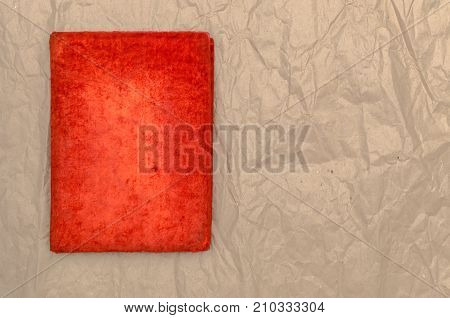 Closed vintage red book isolated on crumpled paper page surface background with copy space.