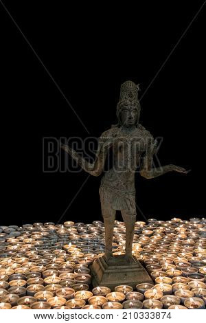 Hindu Goddess Lakshmi bronze statue by candlelight. Many candles for Deepavali Festival of Lights. Hinduism national holiday celebration image.