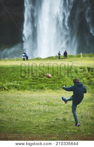 man playing the ball near famous Seljalandsfoss waterfall in southern Iceland. treking in Iceland. Travel and landscape photography concept