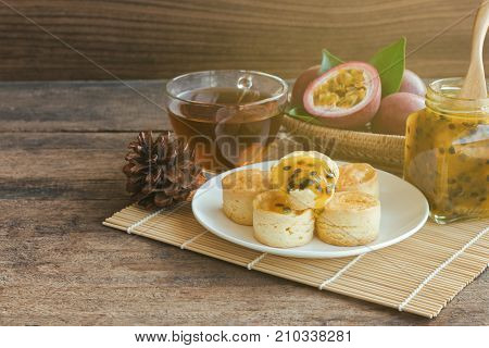 Homemade delicious plain scones serve with passion fruit jam and tea on wood table copy space for background or wallpaper. Scones is traditional English pastry for afternoon tea or coffee break. Scone and passion fruit jam ready to served.