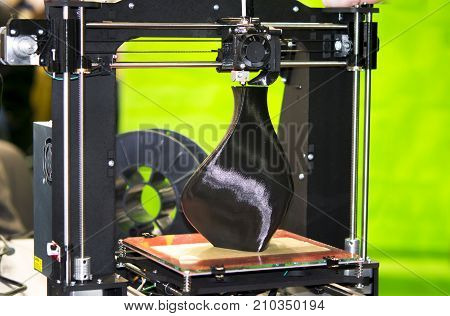 3D printer printing a model in the form of black vase close-up. The concept modern additive technology. The 4ht industrial revolution.