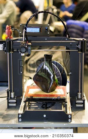 3D printer printing a model in the form of black vase close-up. The concept modern additive technology. The 4ht industrial revolution.