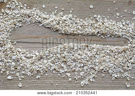 Brown raw cereals in form of spoon are on the wooden background