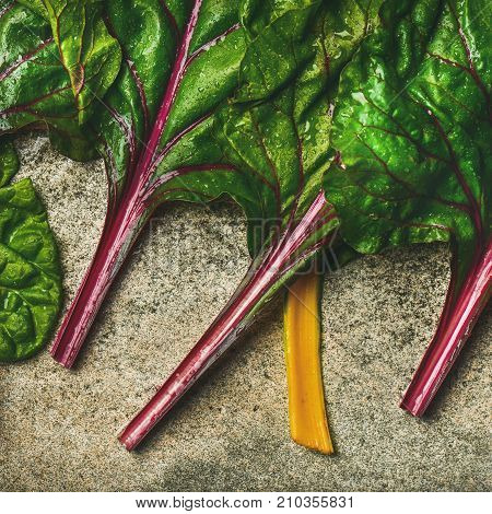 Flat-lay of fresh leaves of swiss chard over concrete stone background, top view, square crop. Clean eating, vegetarian, vegan, alcaline diet, organic, healthy cooking concept