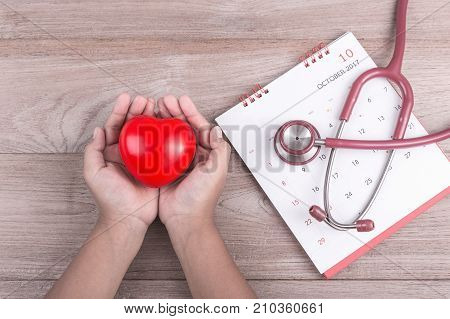 Check Heart Concept : Woman Hands Holding Red Heart And Stethoscope On Brown Wooden Table