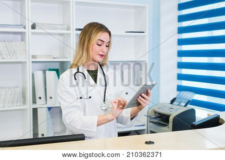 Young female receptionist holding tablet computer in hospital.