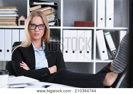 Business woman resting in the office after a working day throwing her feet on the table leaning back her hands behind her head