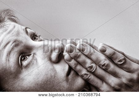 Dramatic black and white image of a woman during a prayer on light background.