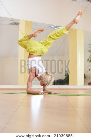 Beautiful sporty fit yogi woman practices yoga asana Vrischikasana Scorpion pose in the yoga class