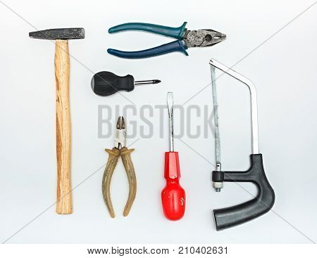 A set of tools on a white background. Pliers hammer side cutters saw and screwdrivers. Authentic tools with traces of use.