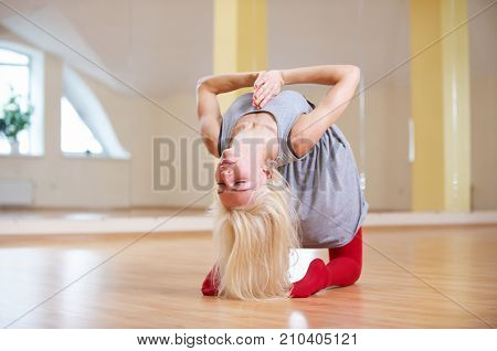 Beautiful young woman practices yoga asana Ushtrasana - Camel pose in the yoga class.