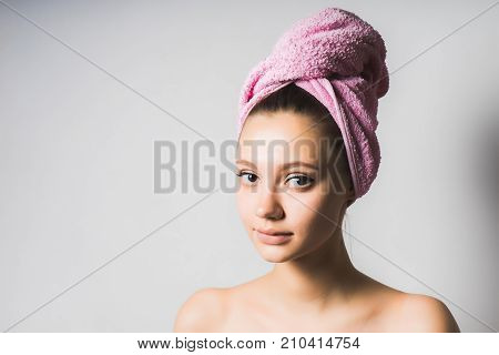 young beautiful girl with clean skin and with a pink towel on her head looking at the camera