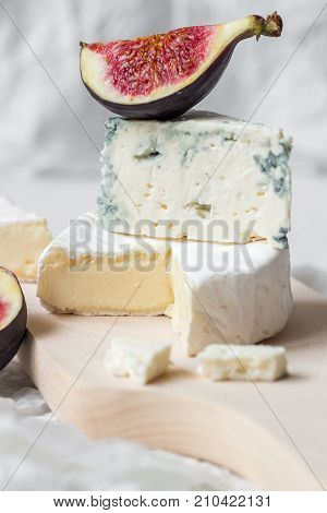 Sliced Fresh Camembert Cheese And Blue Cheese With Figs On The White Wooden Table.